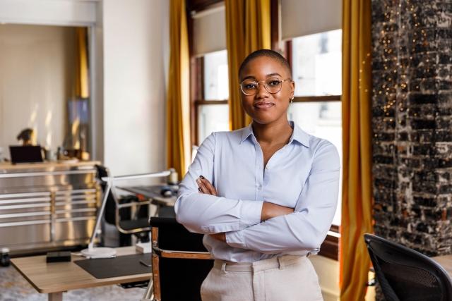 Woman poses near brick wall in office