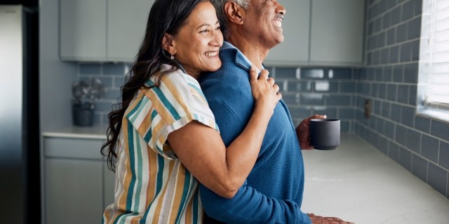 Smiling couple looking out a kitchen window