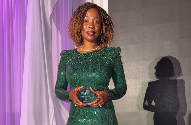 Linda Fombo in a green sparkling dress, holding her KNOW award